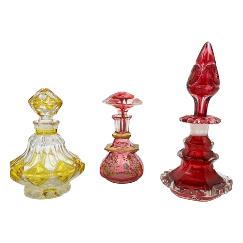 76 - THREE BOHEMIAN GLASS PERFUME BOTTLESA trio of Bohemian glass perfume bottles of varying heights (20c... 