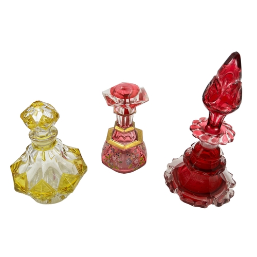 76 - THREE BOHEMIAN GLASS PERFUME BOTTLESA trio of Bohemian glass perfume bottles of varying heights (20c... 