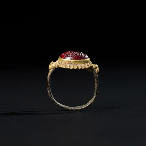 34 - A BRONZE & GOLD SASSANIAN RING WITH ADD ROMAN GARNET INTAGLIO, 3RD CENTURY A unique combination of b... 