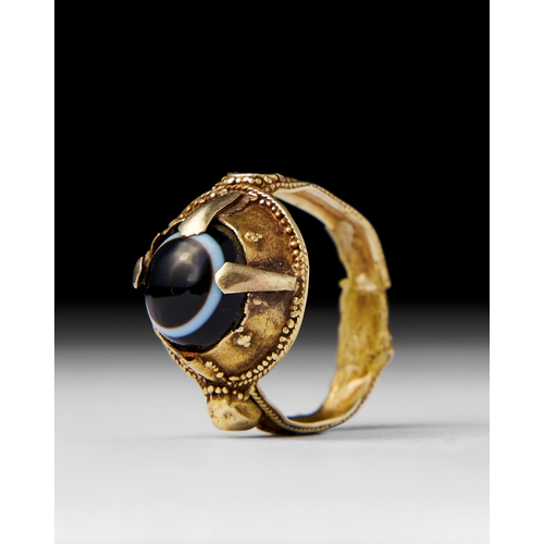 19 - A DZI BEAD EYE RING SET ON GOLD A Dzi bead eye ring features a unique bead with concentric eye patte... 