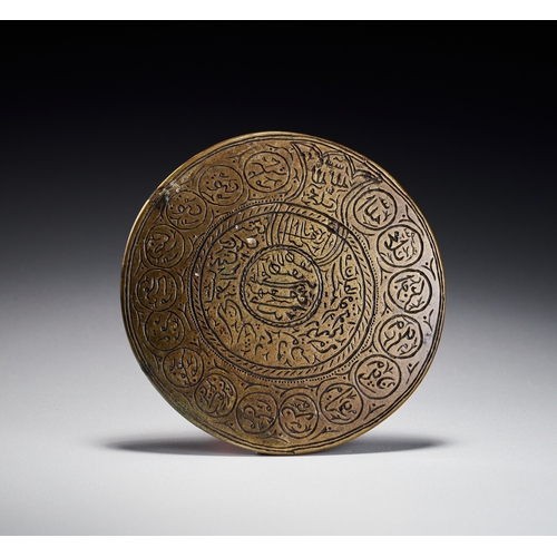 73 - A PERSIAN ENGRAVED BRASS TALISMANIC PLAQUE WITH THE NAMES OF THE TWELVE IMAMS, 19TH CENTURY This cir... 