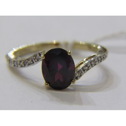 382 - GARNET RING, large oval garnet set on a 9ct yellow gold ring with diamond shoulders of cross over de... 