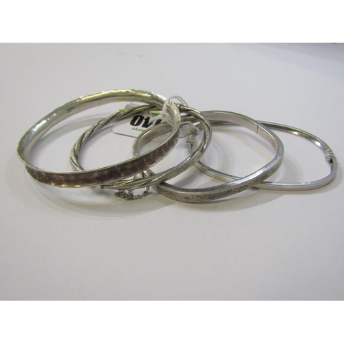 140 - SILVER BANGLES, 4 assorted silver bangles, including 2 hinged bangles and 2 others with engraved dec... 