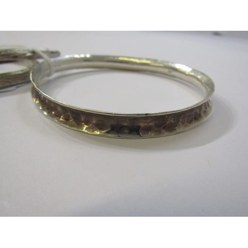 140 - SILVER BANGLES, 4 assorted silver bangles, including 2 hinged bangles and 2 others with engraved dec... 