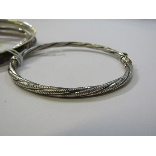 140 - SILVER BANGLES, 4 assorted silver bangles, including 2 hinged bangles and 2 others with engraved dec... 