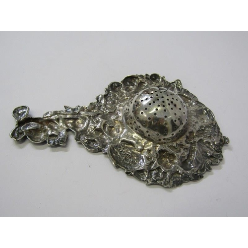 182 - SILVER TEA STRAINER, ornate tea strainer with cupid finial and fruit decoration in relief to the out... 