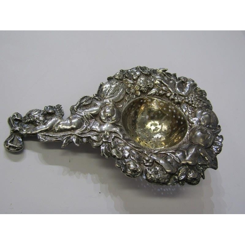 182 - SILVER TEA STRAINER, ornate tea strainer with cupid finial and fruit decoration in relief to the out... 