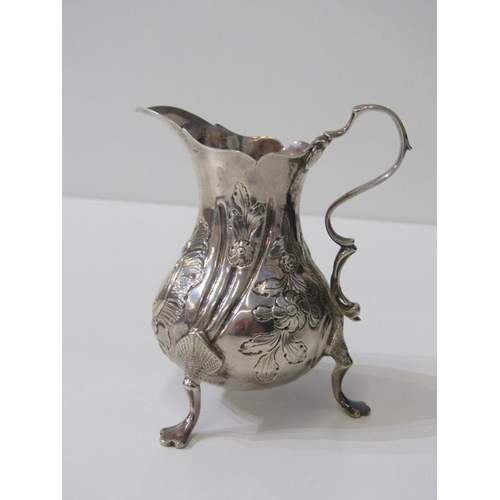 250 - GEORGE III SILVER EMBOSSED CREAM JUG, on tripod feet, London possibly 1763, 91 grams