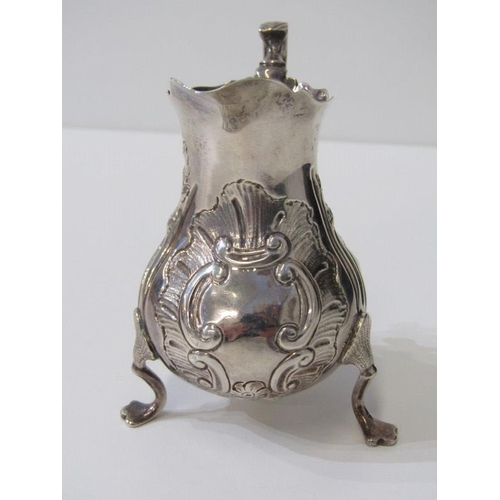 250 - GEORGE III SILVER EMBOSSED CREAM JUG, on tripod feet, London possibly 1763, 91 grams