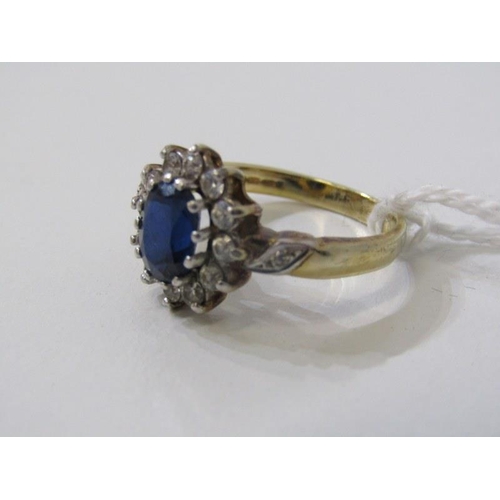 143 - SAPPHIRE CLUSTER RING, oval sapphire surrounded by a cluster of clear stones on a yellow gold mount,... 