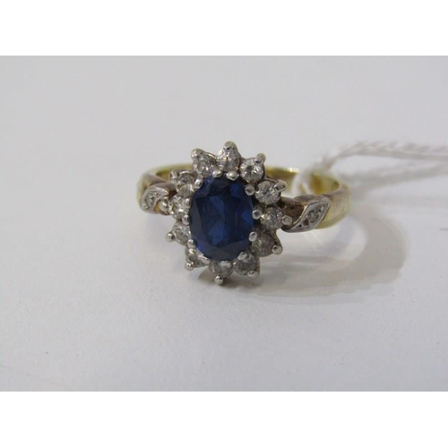 143 - SAPPHIRE CLUSTER RING, oval sapphire surrounded by a cluster of clear stones on a yellow gold mount,... 