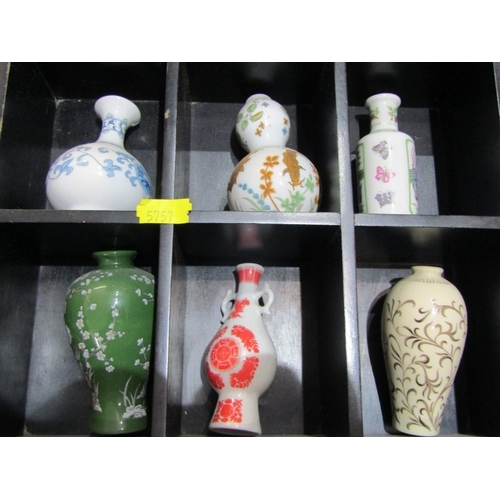 415 - ORIENTAL CERAMICS, 12 various small oriental vases contained in a wood stand