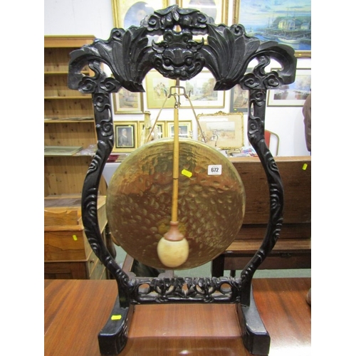 672 - DINNER GONG, a late 19th Century dinner gong, hammered brass gong on an ebonised oriental design fra... 