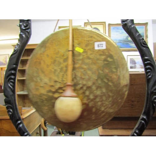 672 - DINNER GONG, a late 19th Century dinner gong, hammered brass gong on an ebonised oriental design fra... 