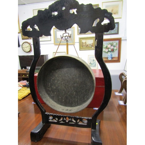 672 - DINNER GONG, a late 19th Century dinner gong, hammered brass gong on an ebonised oriental design fra... 