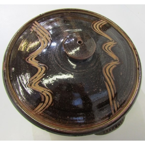 25 - WENFORD POTTERY CASSEROLE DISH, a lidded casserole dish with a dark brown glaze, incised with wavy l... 