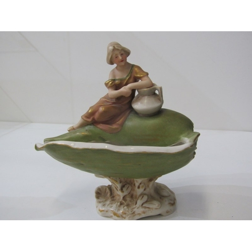 9 - ROYAL DUX, a Royal Dux Bohemia porcelain figure depicting a maiden with a water jug sitting on a lar... 