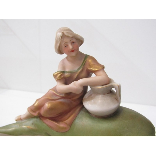 9 - ROYAL DUX, a Royal Dux Bohemia porcelain figure depicting a maiden with a water jug sitting on a lar... 