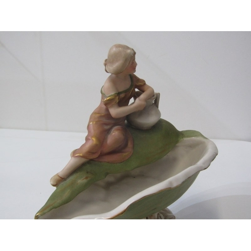 9 - ROYAL DUX, a Royal Dux Bohemia porcelain figure depicting a maiden with a water jug sitting on a lar... 