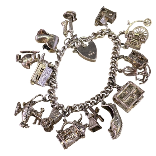32 - A vintage 925 silver curb-link charm bracelet,
hung with a varied collection of articulated and nove... 