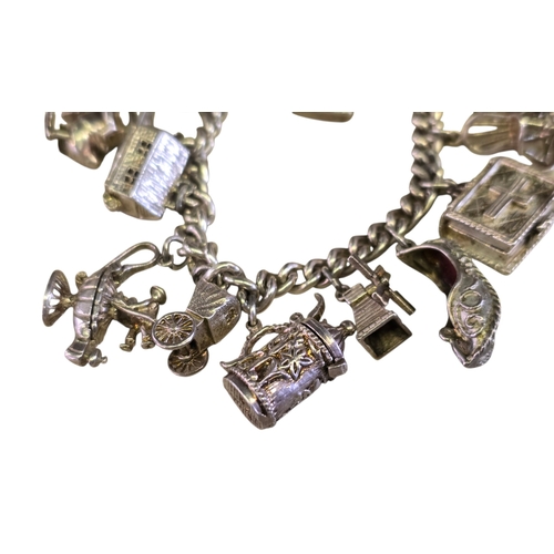 32 - A vintage 925 silver curb-link charm bracelet,
hung with a varied collection of articulated and nove... 