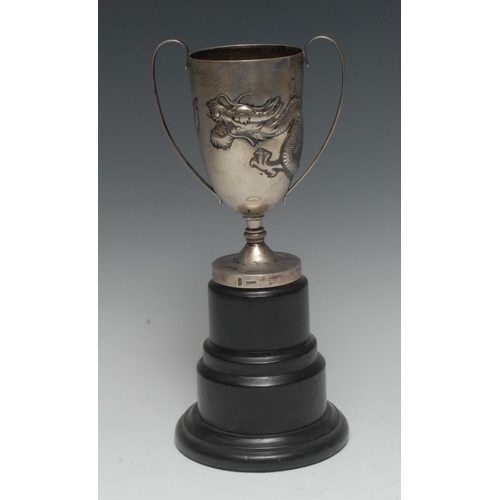 1003 - A Chinese silver presentation cup, repousse chased with a ferocious dragon, scroll handles, domed ci... 