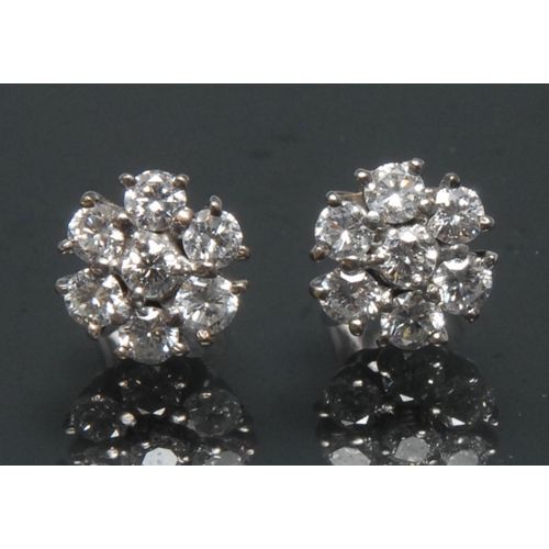 1113 - A pair of seven stone diamond floral cluster earrings, each with a central raised round brilliant cu... 