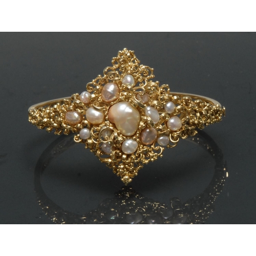 1125 - A blister pearl and 15ct gold hinge bangle, naturalistic scrolling crest, inset with sixteen mixed c... 