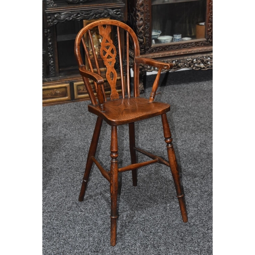 2006 - A 19th century elm and ash child's Windsor high chair, arched back with wheel splat, saddle seat, tu... 