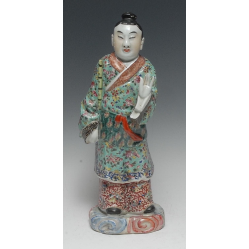 387 - A Chinese porcelain figure, of a musician, he stands in flowing robes holding a bamboo flute, his ot... 