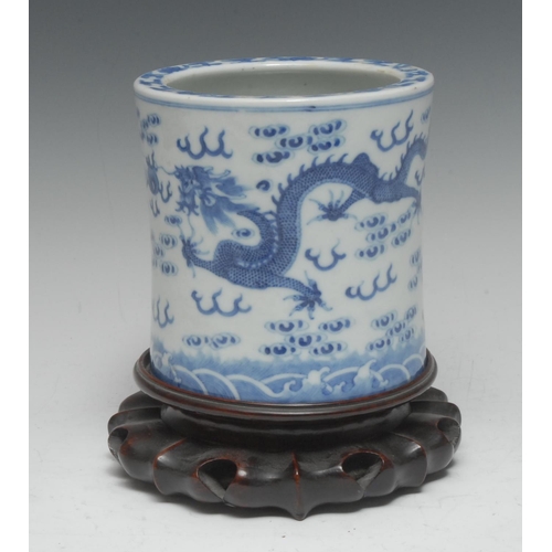 428 - A 19th century Chinese waisted cylindrical brush pot, painted in underglaze blue with dragons chasin... 