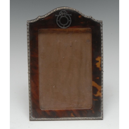 917 - A George V silver, tortoiseshell and pique shaped arched rectangular easel photograph frame, bead-an... 