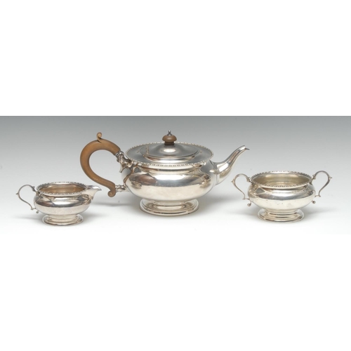 918 - A George V silver three piece tea service, comprising teapot, milk jug and sugar basin, bead-and-ree... 