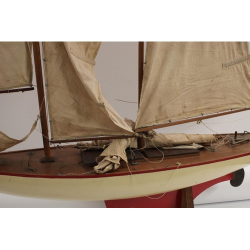 3170 - A large early 20th century pond yacht, The Dolphin, red-line to livery, 117cm long, display stand