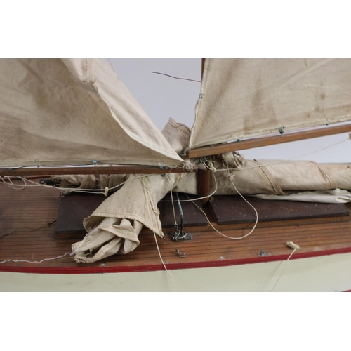 3170 - A large early 20th century pond yacht, The Dolphin, red-line to livery, 117cm long, display stand