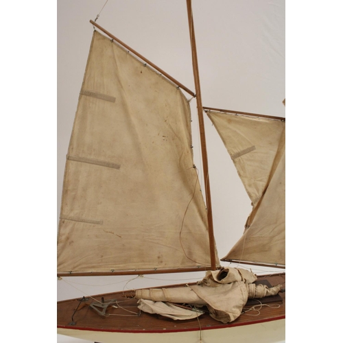 3170 - A large early 20th century pond yacht, The Dolphin, red-line to livery, 117cm long, display stand