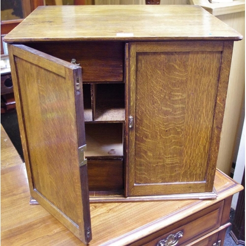 506 - An oak desk cabinet, two doors opening to an arrangement of four drawers and five pigeonholes. 48.5c... 