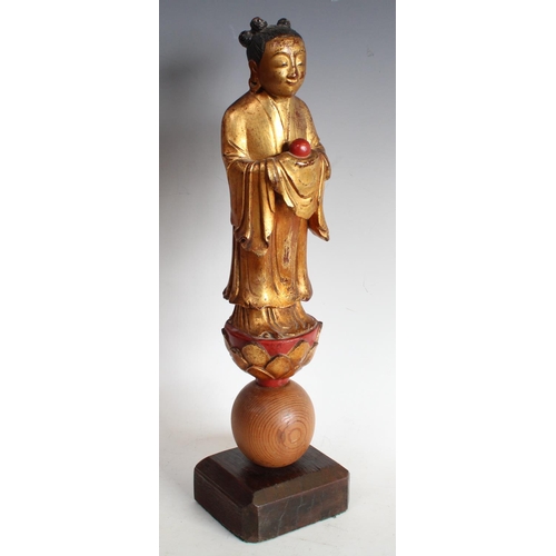 95 - A 19th century Chinese polychrome softwood carving, of an Immortal, standing on a lotus and wearing ... 