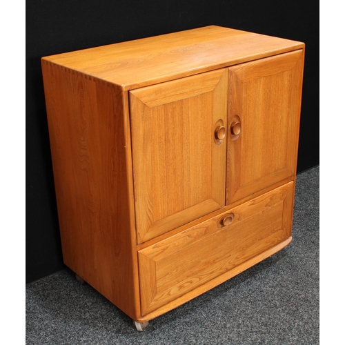 159 - An Ercol elm TV/media cabinet, the two panel doors hinged and retractable above a fall front enclosi... 