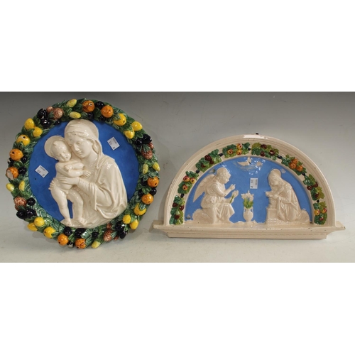 167 - An Italian Majolica circular wall plaque, depicting Mary and Jesus; another, similar arched wall pla... 