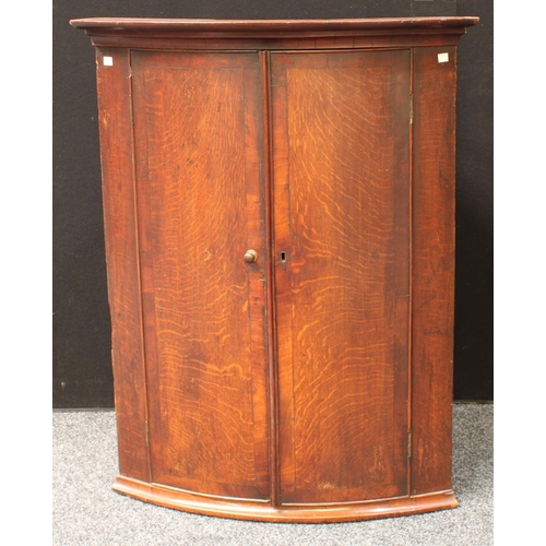 273 - A George III oak bow front corner cupboard, two doors enclosing three shelves, 105cm high