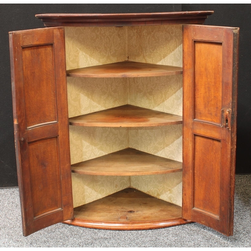 273 - A George III oak bow front corner cupboard, two doors enclosing three shelves, 105cm high