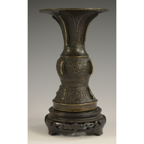 3008 - A 19th century Chinese bronze gu beaker vase, cast in the Archaic manner, 14cm high, hardwood stand