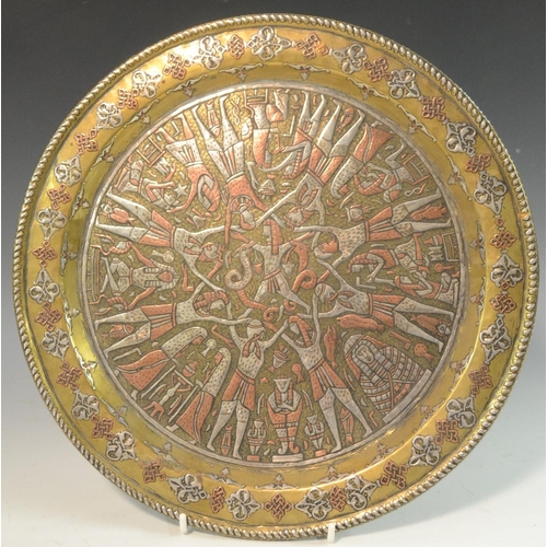 3060 - A Cairo ware circular charger, the field damascened in silver and copper with figures, 30.5cm diam, ... 