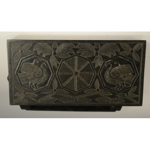 3079 - A Colonial ebony box and cover, carved in relief with stylised birds, palm leaves and geometric moti... 