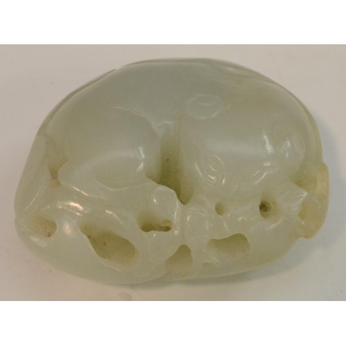 3064 - A Chinese celadon jade carving, of a stylized beast amongst blossoming prunus, 5cm wide