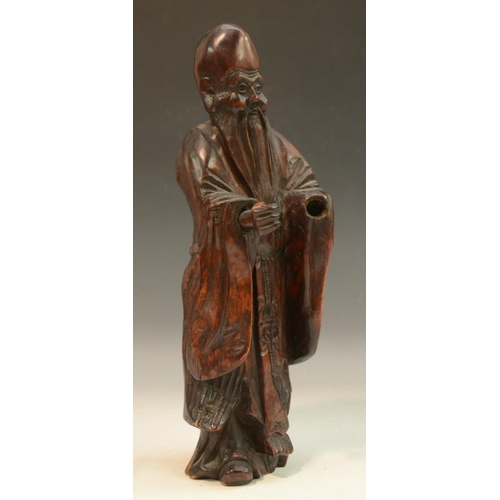 3073 - A Chinese rootwood figure, of a bearded immortal, he stands, wearing long robes, 32cm high, 19th cen... 