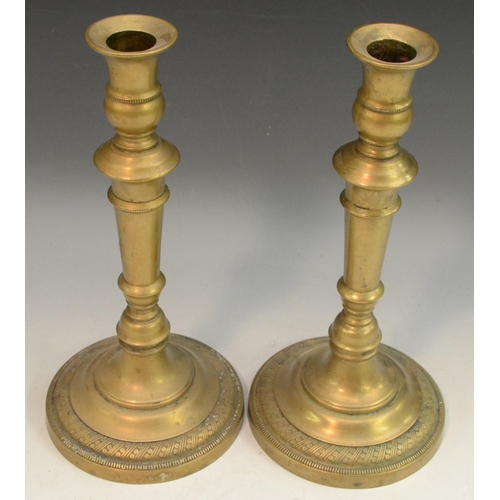 3131 - A pair of French Empire brass candlesticks, campana sconces, knopped stems, circular bases with engi... 