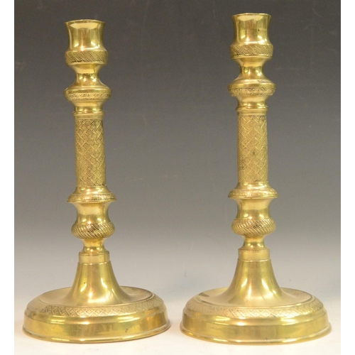 3132 - A pair of French Empire gilt brass table candlesticks, urnular sconces, engine turned with flowerhea... 