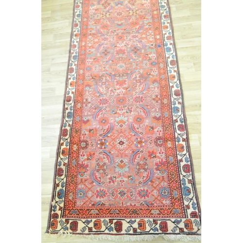 3121 - A Middle Eastern rectangular woollen carpet, the runner with a field of stylised flowers within guar... 